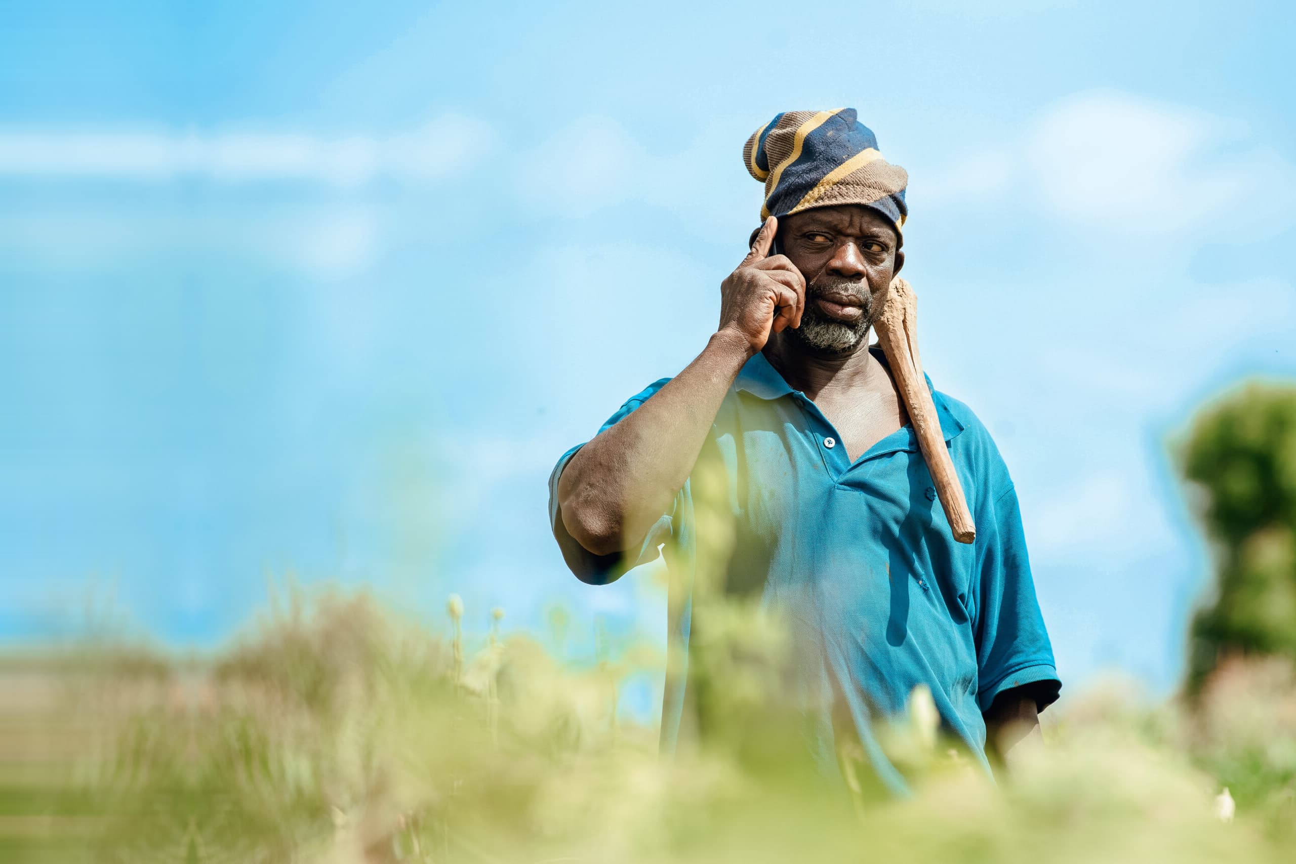 A farmer in the field taking a voice call on his phone