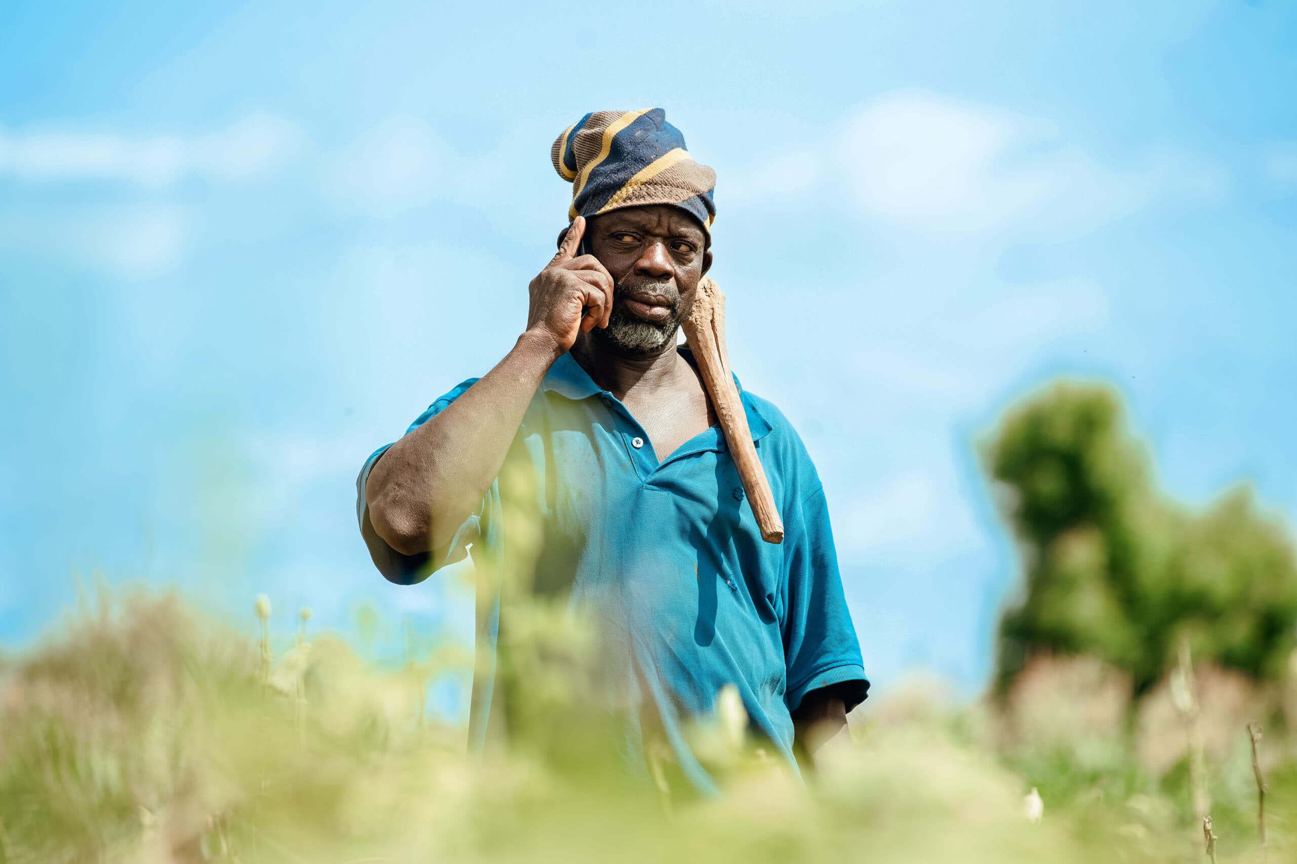 A farmer in the field taking a voice call on his phone